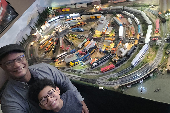 Thomas and his son pose with the family’s model railroad.